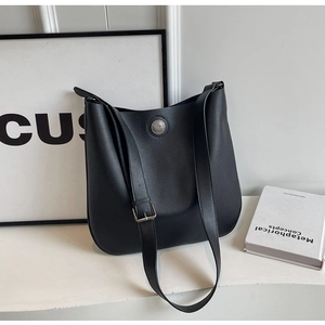 Minimalist black PU leather tote bag with round metal badge and adjustable strap