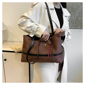Sac cabas en velours marron avec sangles en cuir noir et gland coloré sur manteau blanc