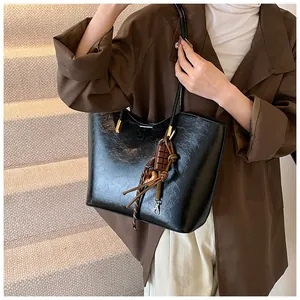 Détail du sac cabas en cuir PU brillant noir avec pendentif chocolat et détails dorés