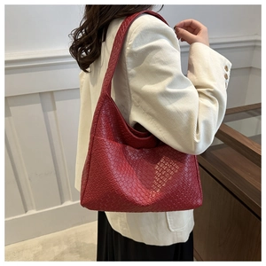 Detail shot of deep red woven PU leather texture on a trendy shoulder bag
