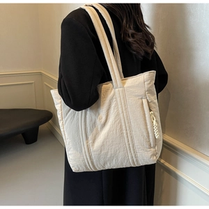Detail of quilted shoulder bag featuring side hidden zipper and braided cord puller