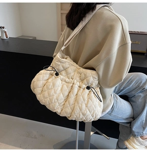 Detail view of quilted puffer bag showing the rhombus texture and adjustable drawstring strap