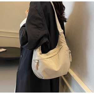 Detail of cream nylon crescent crossbody bag with woven knot zipper and wide strap