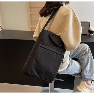 Detail einer großen schwarzen Nylon-Schultertasche mit breitem Gurt und Reißverschluss