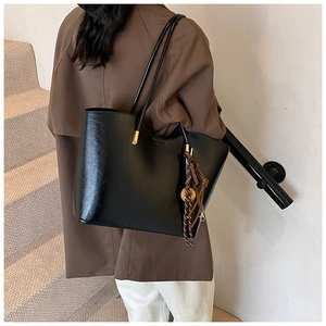 Gros plan détaillé d'un grand sac cabas noir en cuir PU brillant avec ferrures dorées