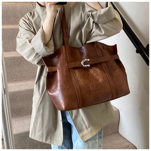 Dettaglio di una borsa tote in ecopelle marrone con fibbia a U argentata e tracolla lunga
