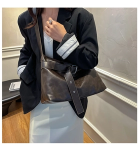 Side view of dark brown faux leather crossbody bag with decorative straps and metal eyelets