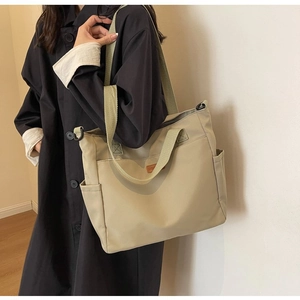 Detail of khaki canvas tote bag with brown leather patch and side pocket for daily commuting