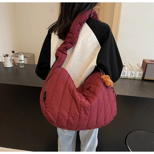 Detail of burgundy quilted Hobo bag featuring a cute brown plush bear charm and zip pocket