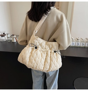 Detail of quilted beige shoulder bag featuring drawstring closure and nylon fabric