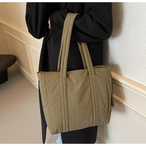 Detail view of olive green fabric tote bag with quilted straps and side zipper pocket