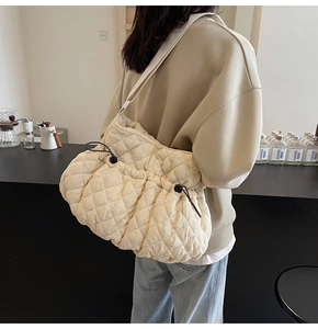 Detail view of beige quilted cloud bag with drawstring closure and wide fabric strap