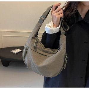 Detail view of neutral green crescent bag with woven zipper pulls and wide strap