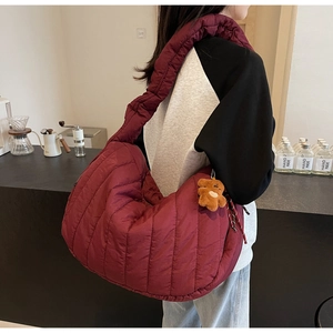 Detail of burgundy quilted shoulder bag featuring soft texture and cute brown teddy bear charm