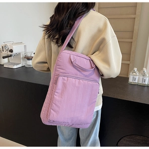 Rückansicht eines Modells mit einer lila Umhängetasche aus Nylon in einem Café