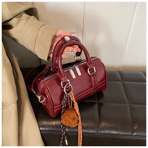 Detail of burgundy bowling bag in glossy leather with a cute plush bear charm pendant