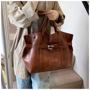 Dettaglio della borsa tote in pelle PU color caramello con fibbia a C e logo inciso
