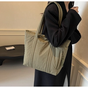 Detailed view of olive green quilted nylon tote bag with durable woven rope zipper pull