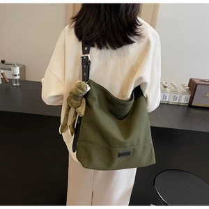 Detail view of military green canvas tote bag with adjustable black leather shoulder strap