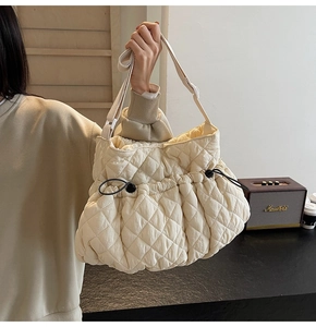 Detail of off-white quilted nylon shoulder bag with drawstring closure and wide strap