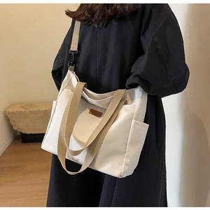 Detail view of cream canvas tote bag with adjustable shoulder straps and leather logo patch