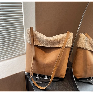 Brown suede shoulder bag with off-white sherpa trim and adjustable strap in warm sunlight