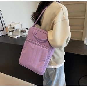 Detail der lila Nylon-Tragetasche mit Reißverschluss-Fronttasche am Modell im Café