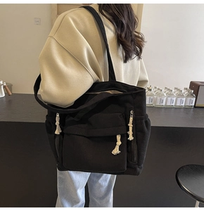 Détail d'un grand sac cabas noir en velours côtelé avec fermetures en corde de coton blanc