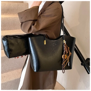 Détail d'un grand sac cabas noir en cuir PU avec pendentif tissé porté par un mannequin