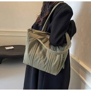 Detail view of olive green tote bag featuring vertical stitching and woven rope zipper pull