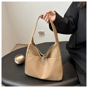 Detailed side view of beige PU leather tote bag with woven texture and open side pocket