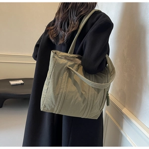 Detailed view of olive nylon tote bag with wide handles and woven zipper puller