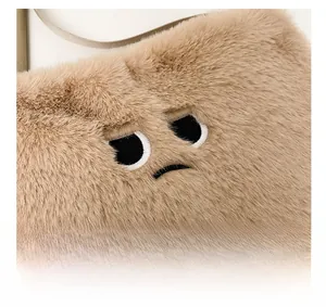 Dettaglio ravvicinato della borsa di peluche kaki con ricamo di una faccia buffa