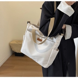Detail of off-white canvas tote bag with khaki straps and side pockets for commuting