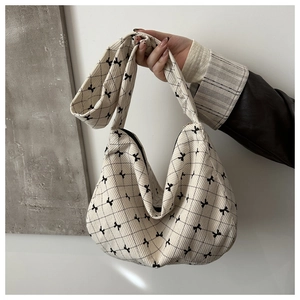 Dettaglio della borsa tote in tela con motivi a fiocco nero e texture a rombi trapuntati