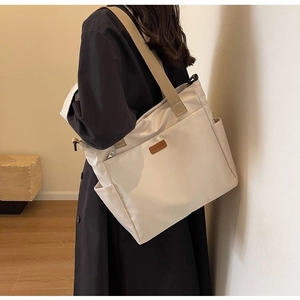 Minimalist cream canvas tote bag with brown leather logo and wide khaki shoulder strap details