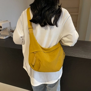 Mustard yellow nylon dumpling crossbody bag with adjustable wide strap and woven zipper pull
