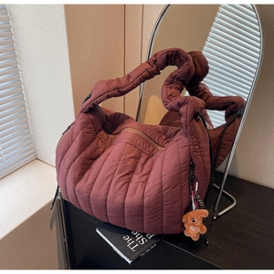 Detailed view of burgundy quilted tote bag with soft fabric and brown bear plush charm