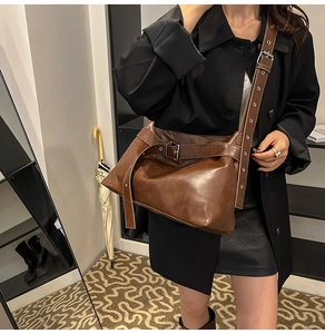 Detail of dark brown PU leather crossbody bag with silver metallic buckle and vintage strap