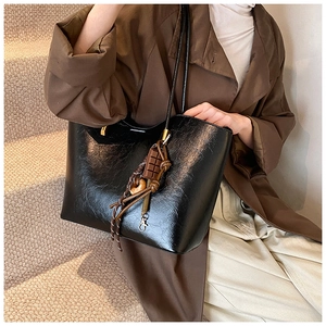 Détail du grand sac cabas noir en similicuir brillant avec des breloques fantaisies