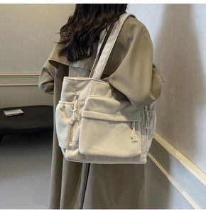 Détail du sac fourre-tout en velours côtelé blanc cassé avec poches zippées et pompons