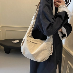 Minimalist beige crescent crossbody bag with woven rope detail and nylon texture
