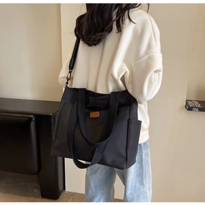 Detailed back view of a black large canvas tote bag with adjustable shoulder strap on model