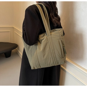 Detail of olive green nylon tote bag with vertical stitching and side zipper pocket