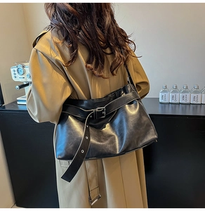 Detail view of stylish black PU leather shoulder bag with glossy finish and metal buckle