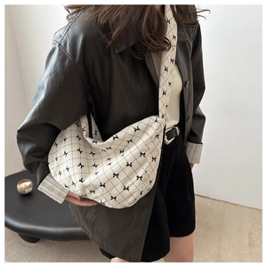 Dettaglio della borsa hobo con trama a rombi neri e fiocchi su tessuto color crema