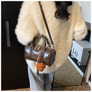 Detail of dark brown faux leather Boston bag with a cute plush dog charm on sweater
