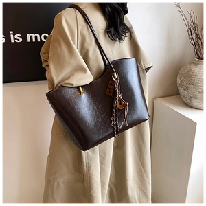 Détail d'un grand sac cabas en cuir marron foncé avec charme chocolat et pompons