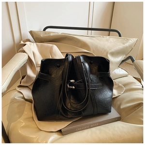 Borsa tote minimalista in pelle PU nera con texture a pieghe sopra un libro base