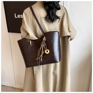 Détail d'un grand sac cabas marron foncé en similicuir avec texture vintage et breloques